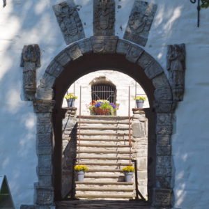 Kultur in Austrått, Schloss Austrått, durch das Tor blicken und Blumen in der Treppe im Inneren zu sehen