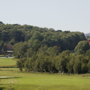 Austrått Golfplatz, Austrått Agrotourismus, teil eines golfplatzesist im Vordergrun zu sehen, wald und einbauernhof im hintergrund