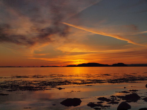 Ørland, der Sonnenuntergang färbt den Himmel orange, der Himmel spiegelt sich im Meer