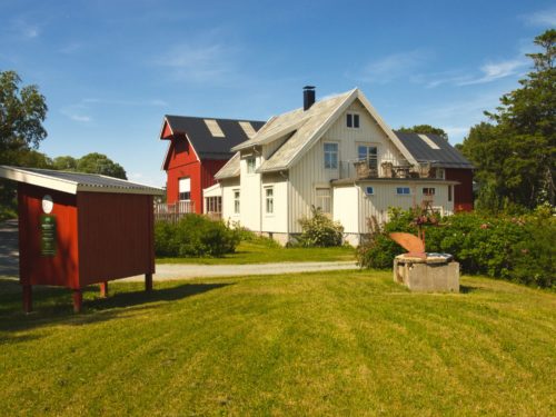 Ørland, Austrått, Austrått agroturisme, Kårstua, rød melkerampe til venstre, hvitt hus i midten, rød låve i bakgrunnen, sol og blå himmel