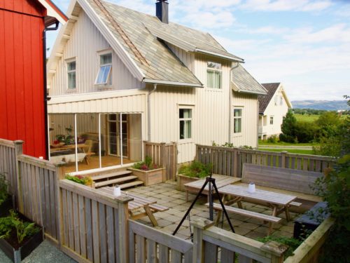 Örland, Austrått agroturismus, im Vordergrund eine Terasse mit Tischen und Bänken, verbunden durch ein Weisses Haus